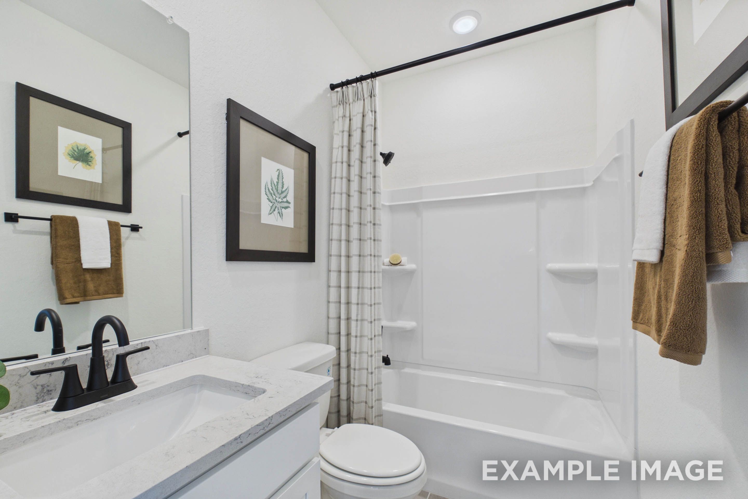 Modern bathroom in The Laurel G floor plan featuring a clean white vanity, quartz countertops, and a tub-shower combo.