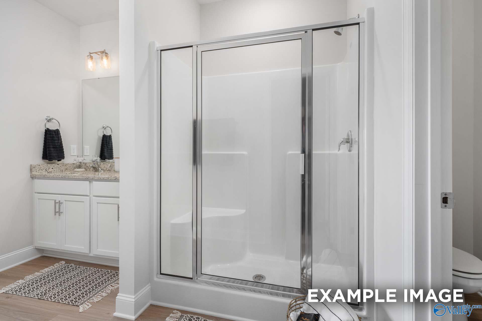 Modern bathroom with double vanity, glass shower enclosure, and toilet in Davidson Homes The Daphne D, Meridianville, Alabama