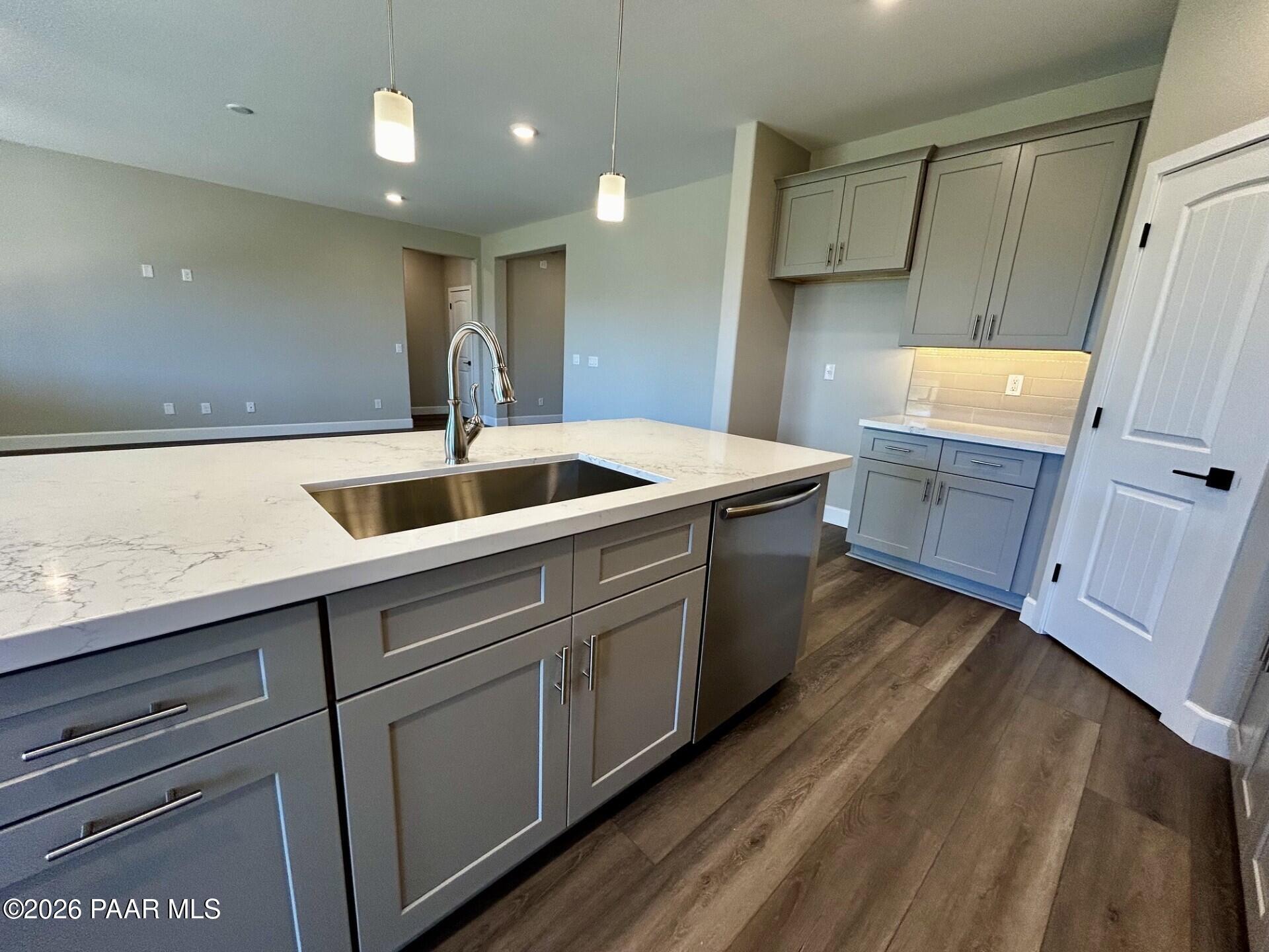 Modern kitchen with gray cabinets, quartz island, and stainless steel sink in The Harmony C plan at Pronghorn Ranch.