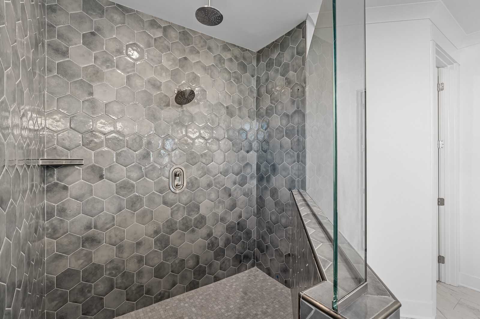 Modern gray hexagonal tile walk-in shower with rainfall head and glass enclosure in Davidson Homes The Hawkins bathroom, Murfreesboro, TN