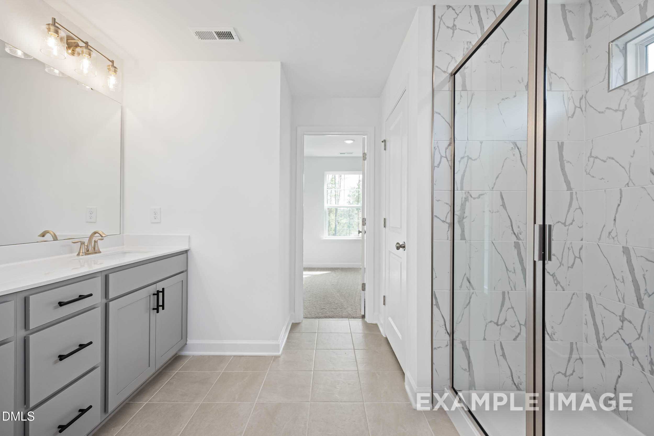 Modern master bathroom with double gray vanity, frameless glass shower, and white subway tiles in Davidson Homes The Willow D, Zebulon, NC