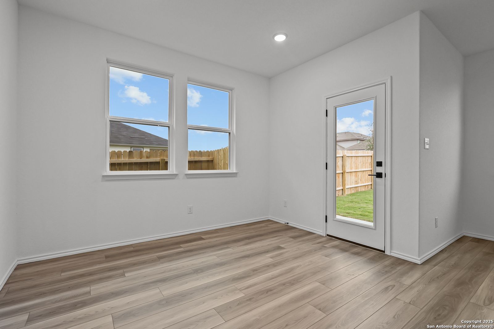 Bright secondary bedroom with large windows, sliding glass door to fenced backyard, hardwood floors in 4-bed The Daphne J, Converse TX