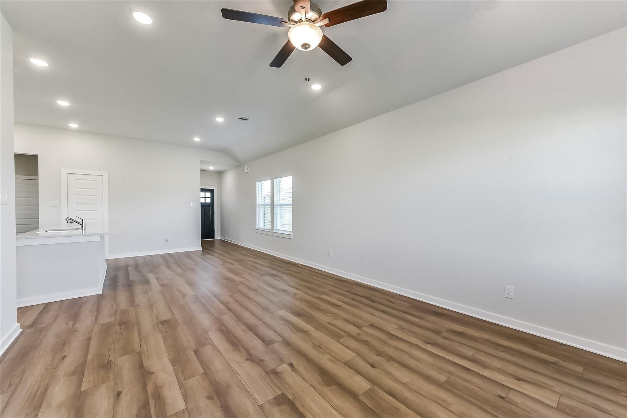 Open living area with ceiling fan, recessed lights, and laminate wood floors in Davidson Homes The Costa B, Dayton, Texas
