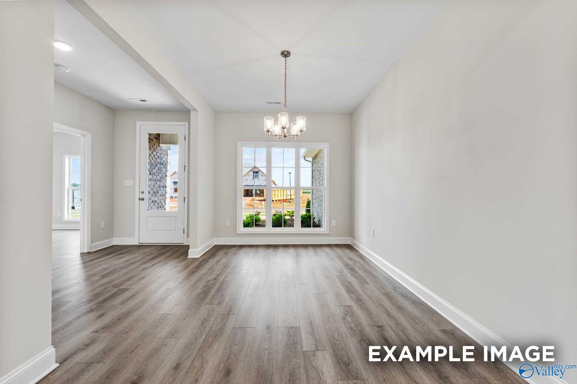 Elegant dining room with chandelier, large windows, and hardwood floors in The Finleigh by Davidson Homes, Meridianville, AL