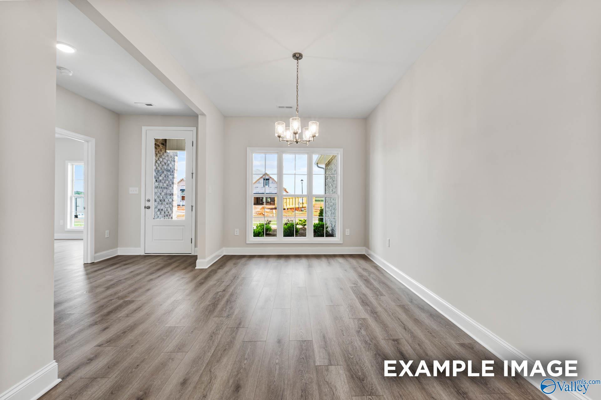 Elegant dining room with hardwood floors, chandelier, and large windows to backyard in The Finleigh by Davidson Homes, Huntsville, AL