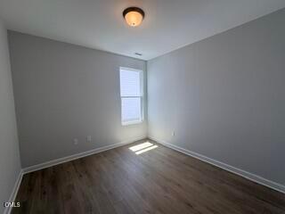 Bright bedroom with neutral gray walls and wood-style flooring in The Daphne D floor plan at Woodland Crossing, Zebulon, NC.