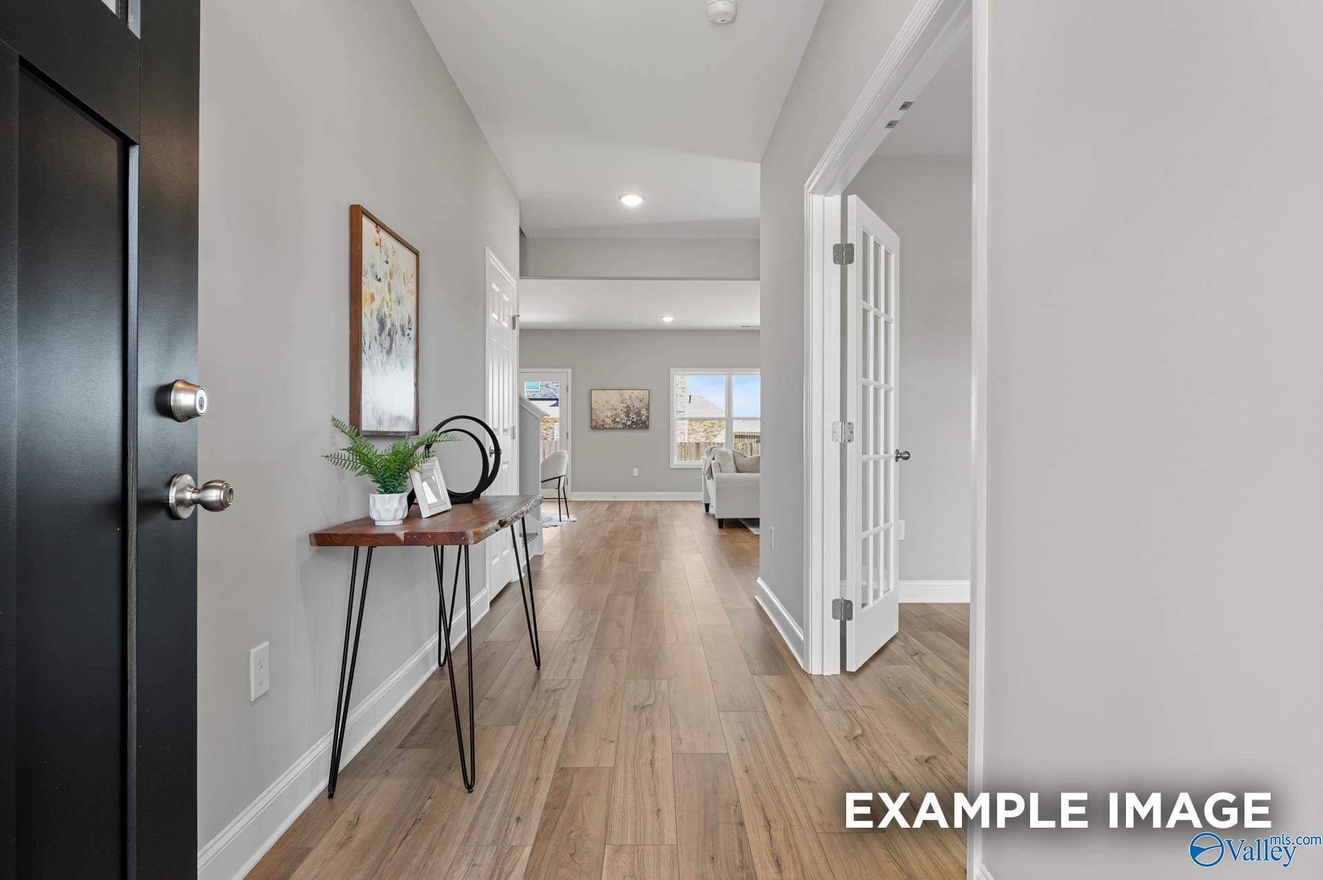 Elegant foyer with black front door, gray walls, hardwood floors, console table, and art in The Chelsea B, Ivy Hills, Toney, Alabama