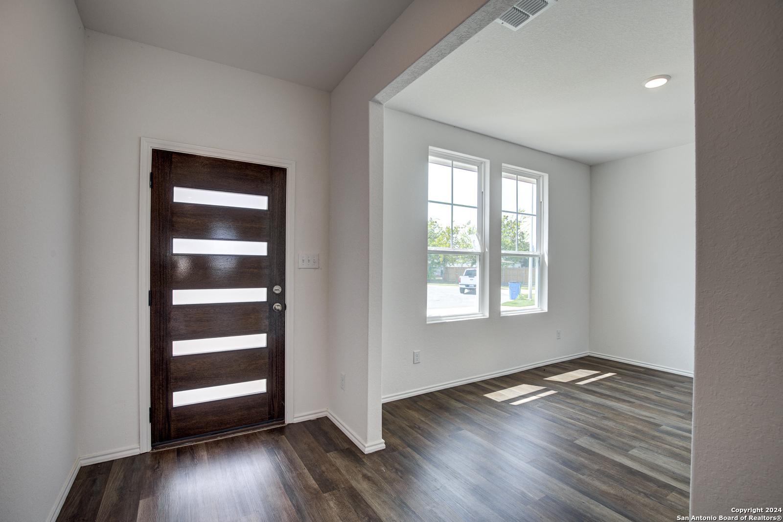 Bright entryway with modern slatted wood door, hardwood floors, and large windows in Davidson Homes The Douglas D, Seguin, Texas