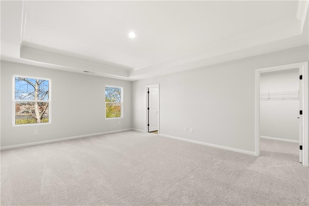 Bright master bedroom with tray ceiling, large windows, walk-in closet in Davidson Homes The Cary A, Winder, Georgia