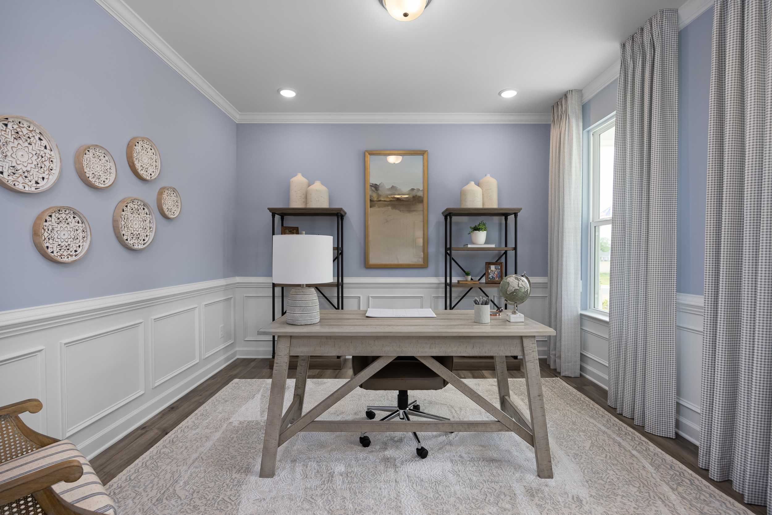 Cozy home office at Tobacco Road in Angier NC with rustic wooden desk, blue walls, wainscoting, and decorative wall plates
