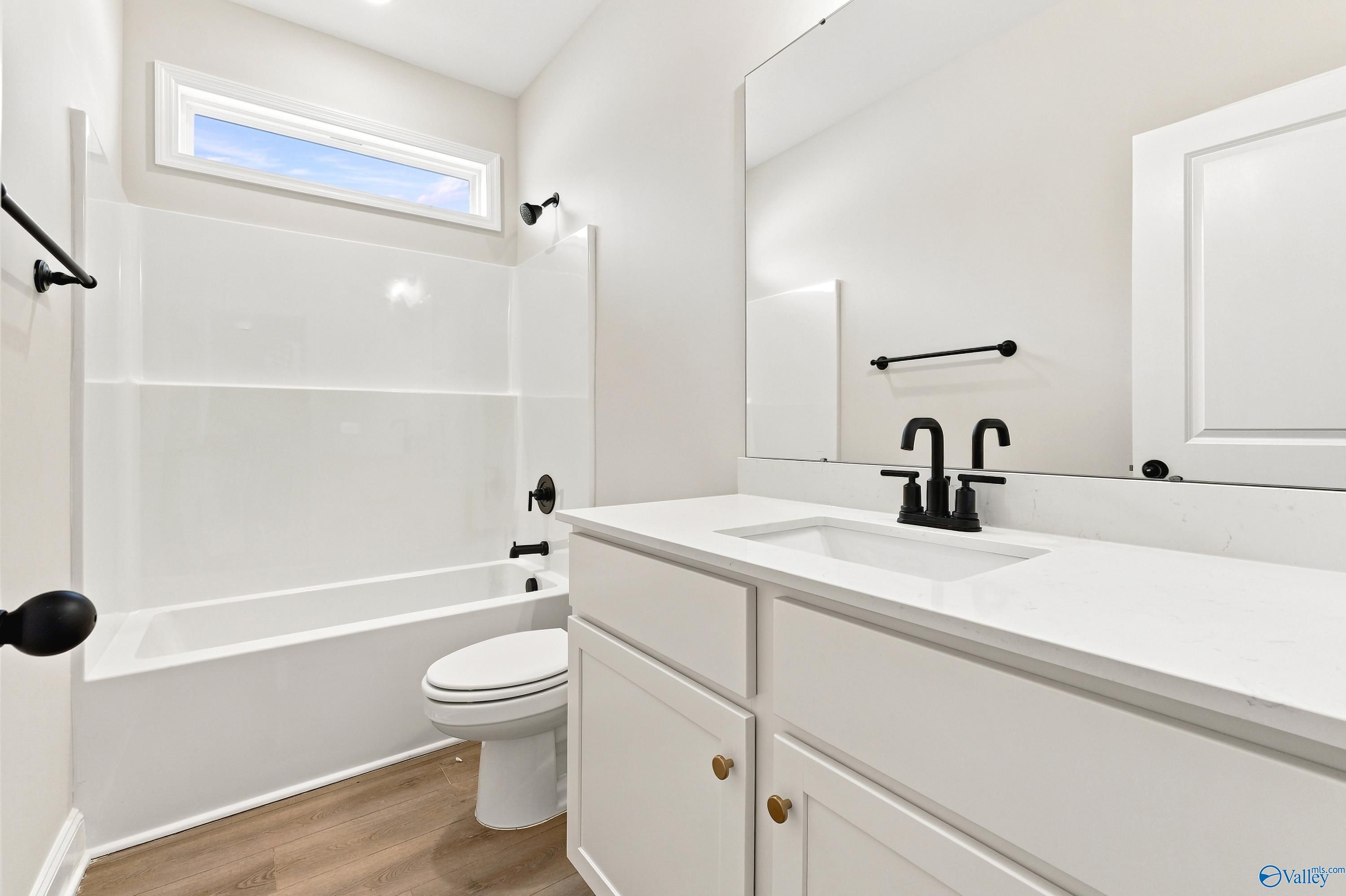 Modern bathroom with white vanity, matte black fixtures, and tub-shower combo in The Daphne floor plan, Meridianville, AL.