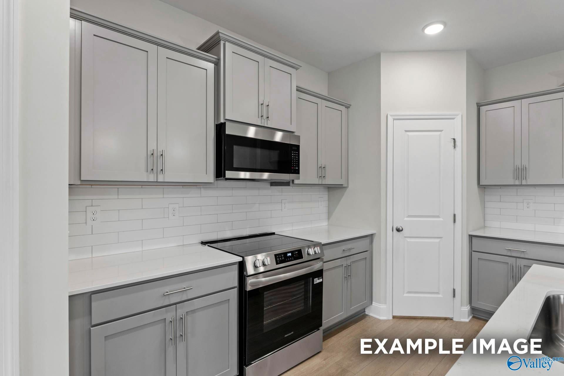 Modern kitchen with gray cabinets, white subway tile backsplash, and stainless appliances in The Franklin C, Cullman, AL.