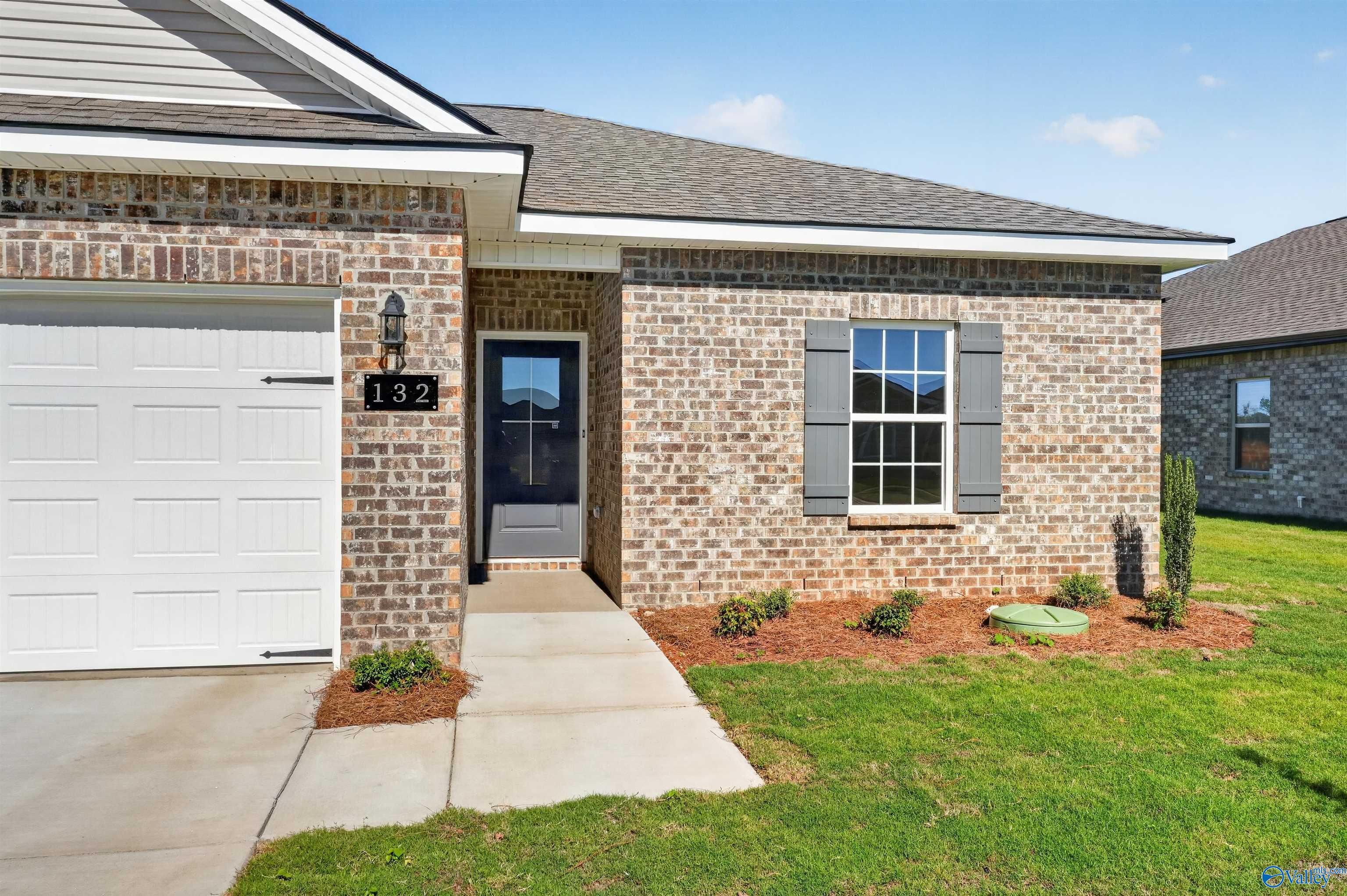 Brick exterior front of Davidson Homes The Butler plan with 2-car garage and landscaped yard in Heritage Lakes, New Market, Alabama