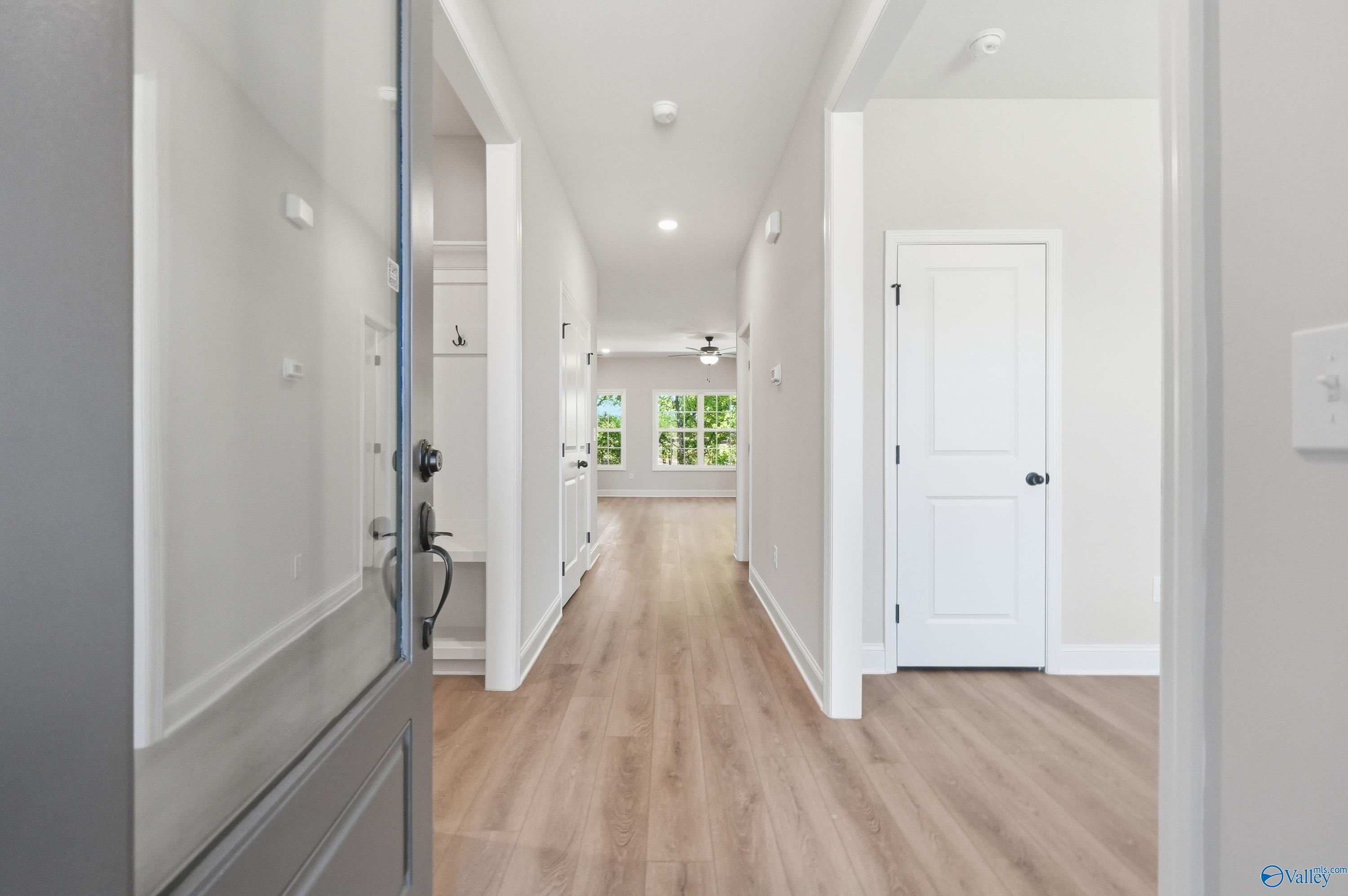 Spacious entry hallway with hardwood floors, white doors, and natural light from windows in Davidson Homes The Rockford B, Athens, AL