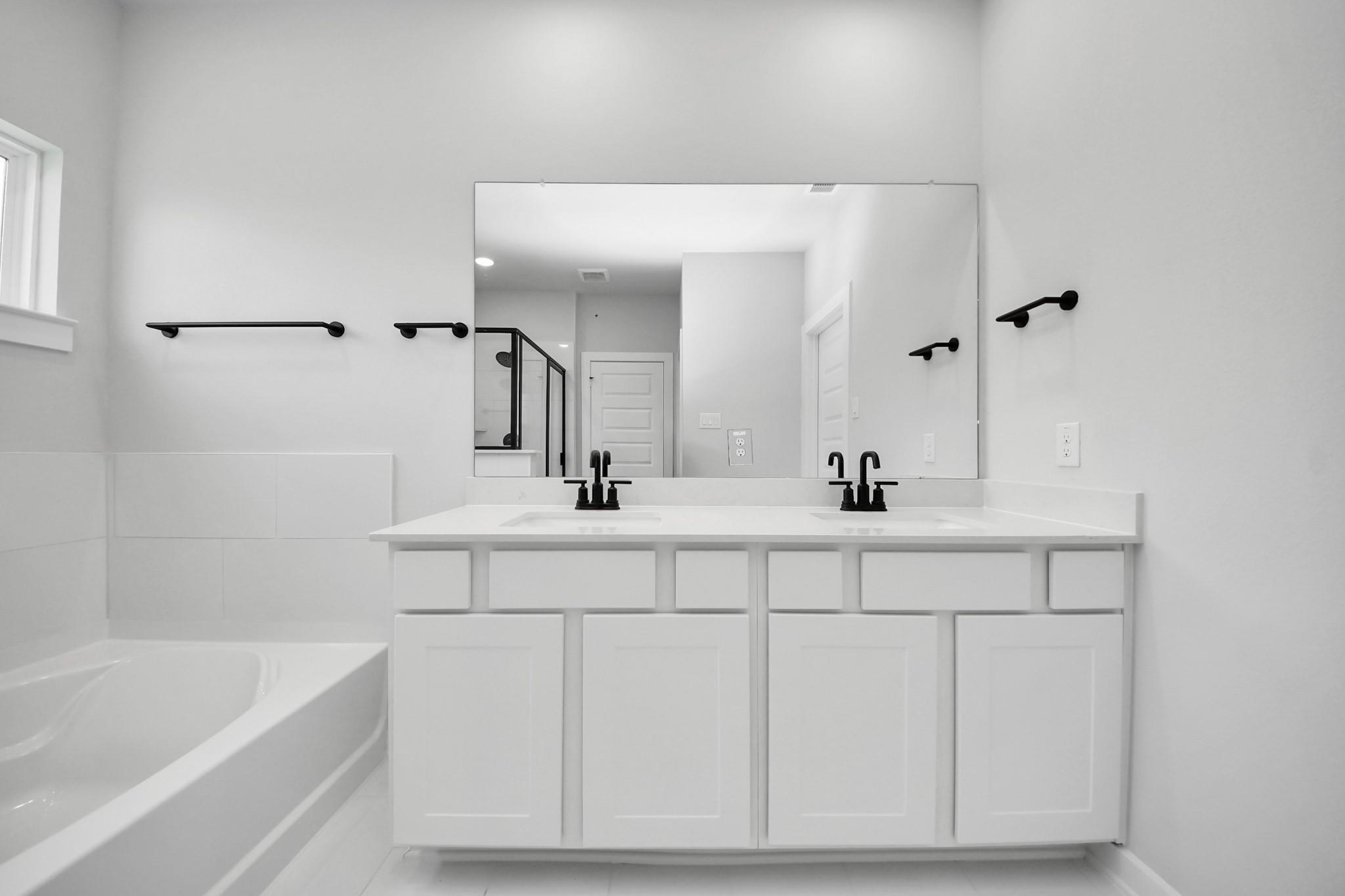 Modern double vanity with matte black fixtures in a Riviera C floor plan primary bathroom in River Ranch Meadows, Dayton.