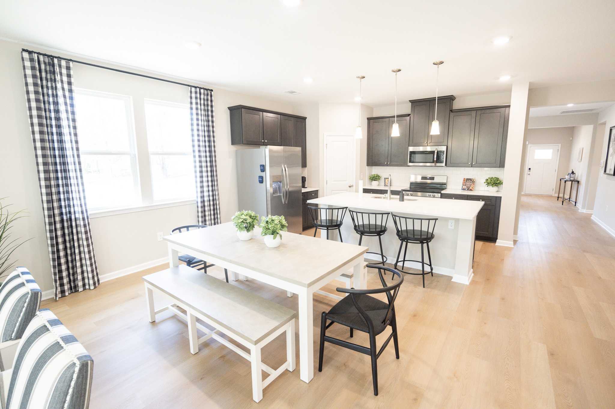 Spacious open-concept kitchen dining area in Silver Oak Cusseta Alabama with white cabinets hardwood floors and pendant lights