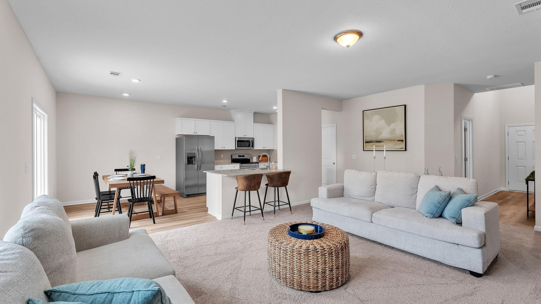 Spacious open-concept living room and kitchen at Summer Vineyard in Phenix City AL with white sofas, island bar, and stainless appliances