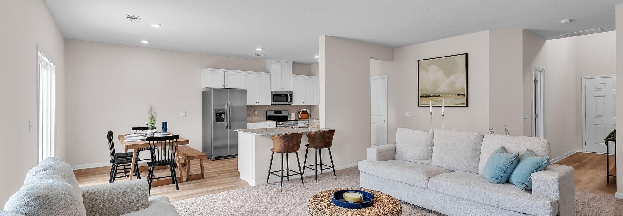 Spacious open-concept living room and kitchen at Summer Vineyard in Phenix City AL with white sofas, island bar, and stainless appliances