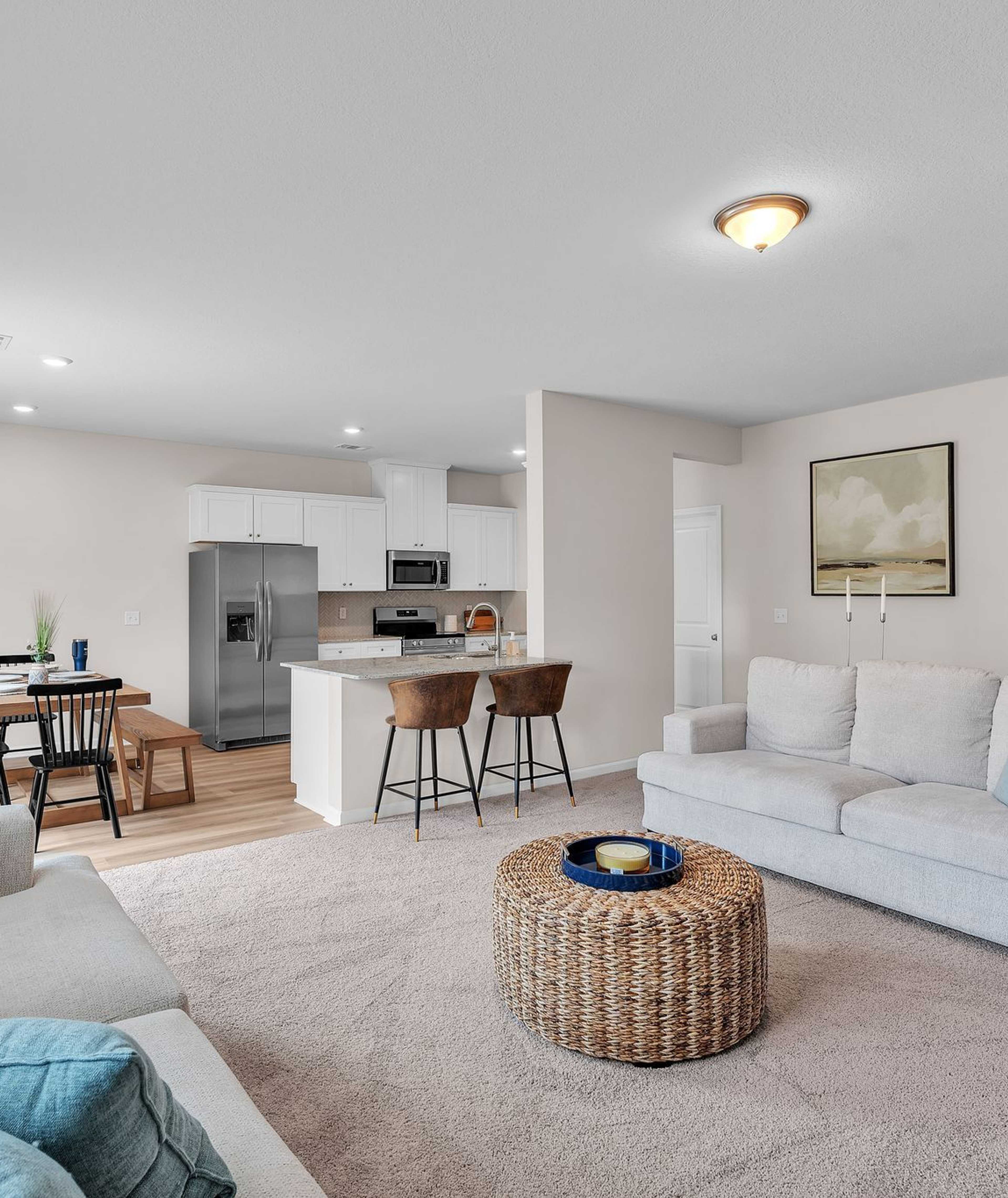 Spacious open-concept living room and kitchen at Summer Vineyard in Phenix City AL with white sofas, island bar, and stainless appliances
