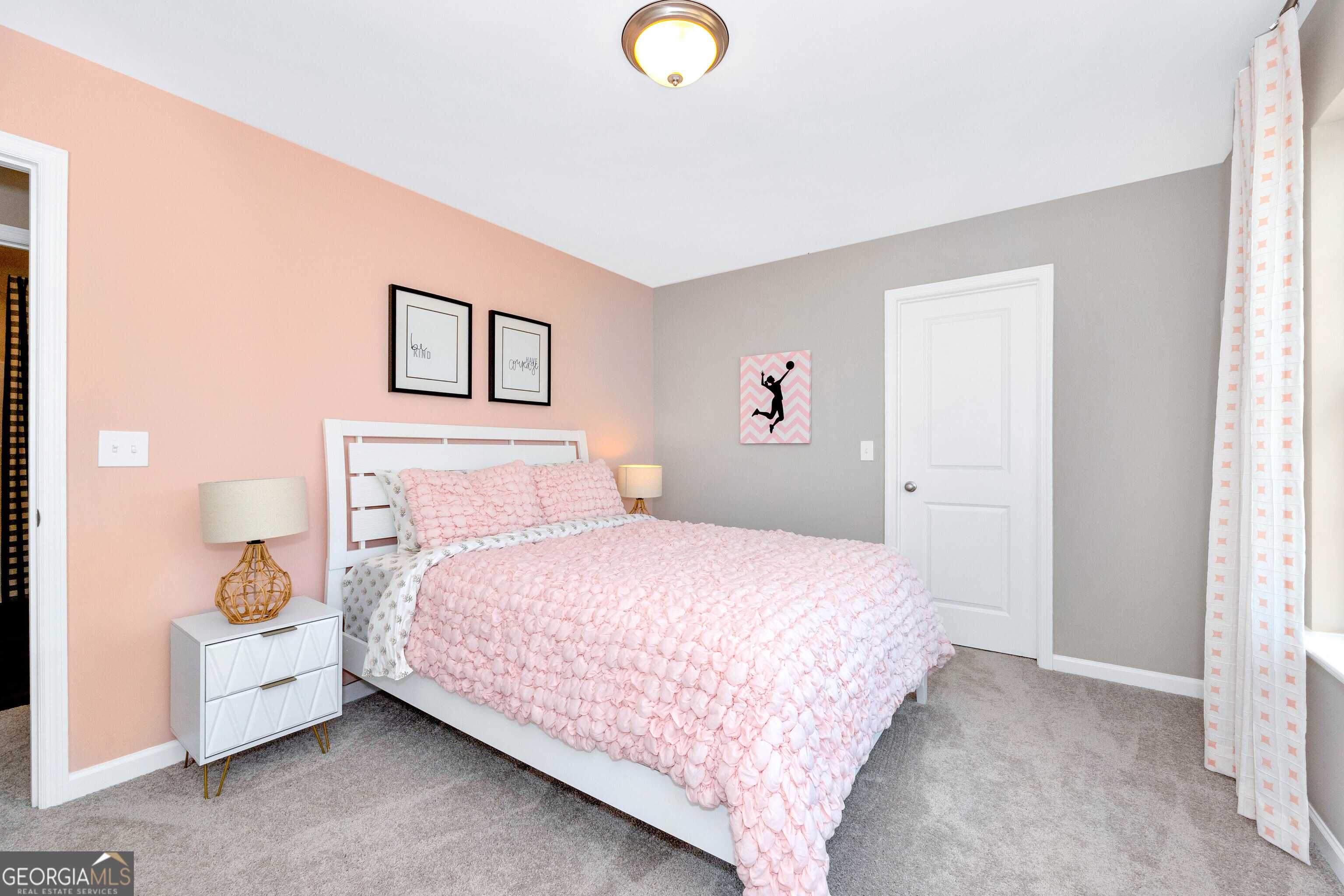 Charming girl's bedroom with pink walls, gray accents, tufted pink bed, and bedside lamps in Evermore Homes The Stella, Perry GA