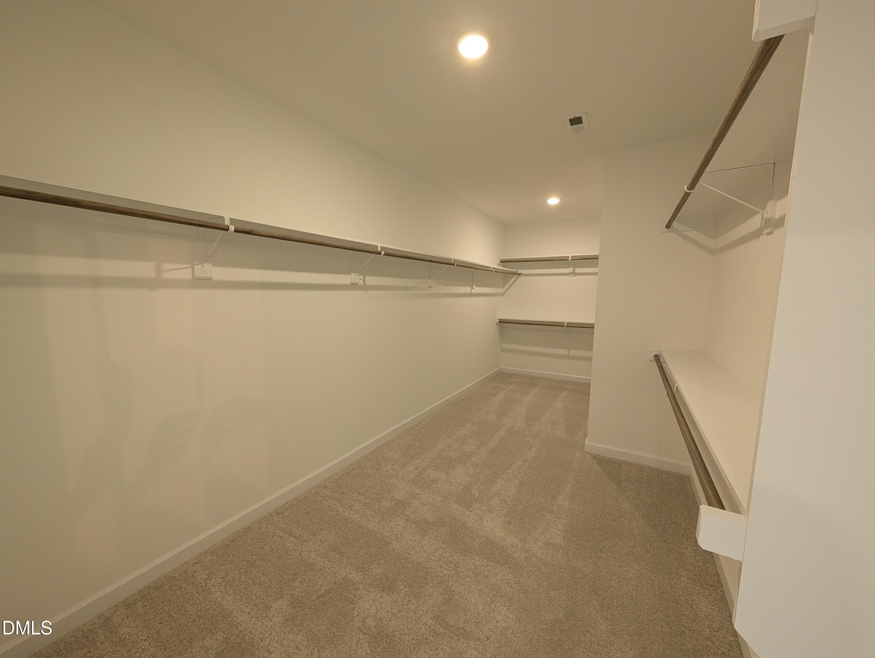 Spacious walk-in closet with carpet and built-in shelving in The Aspen B floor plan at Wendell Ridge, Wendell, NC.