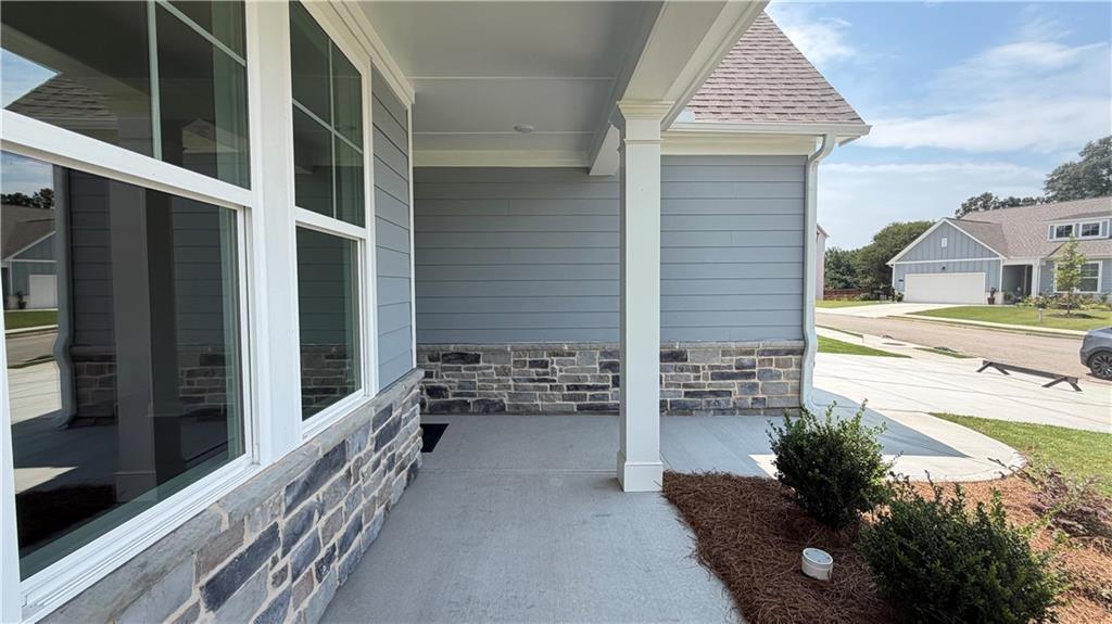 Covered front porch with stone accents and grey siding on The Ash C floor plan in Wehunt Meadows, Hoschton, Georgia.