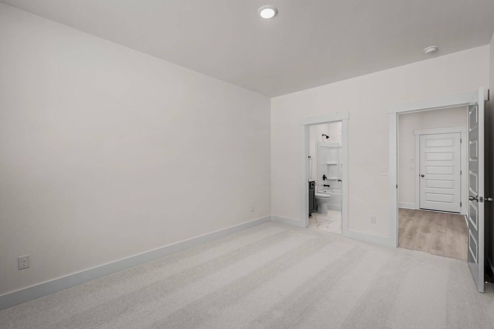 Spacious bedroom with plush carpet and en-suite bathroom in The Willow floor plan at Woods Crossing, Gallatin, Tennessee.
