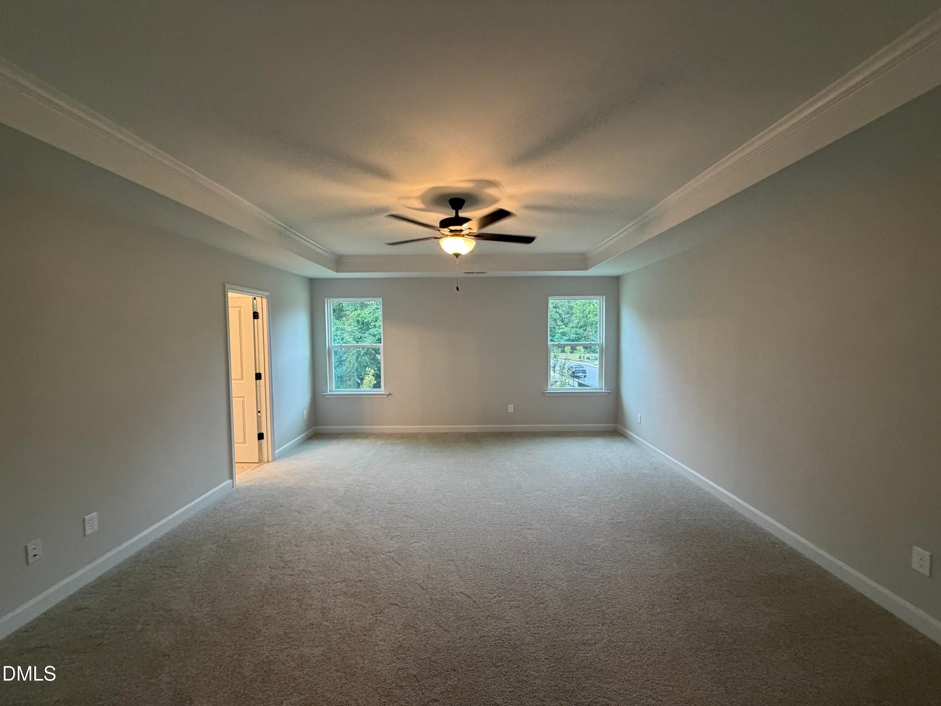 Spacious carpeted bedroom with tray ceiling, ceiling fan, and dual windows in Davidson Homes The Preston C, Wendell Ridge, NC