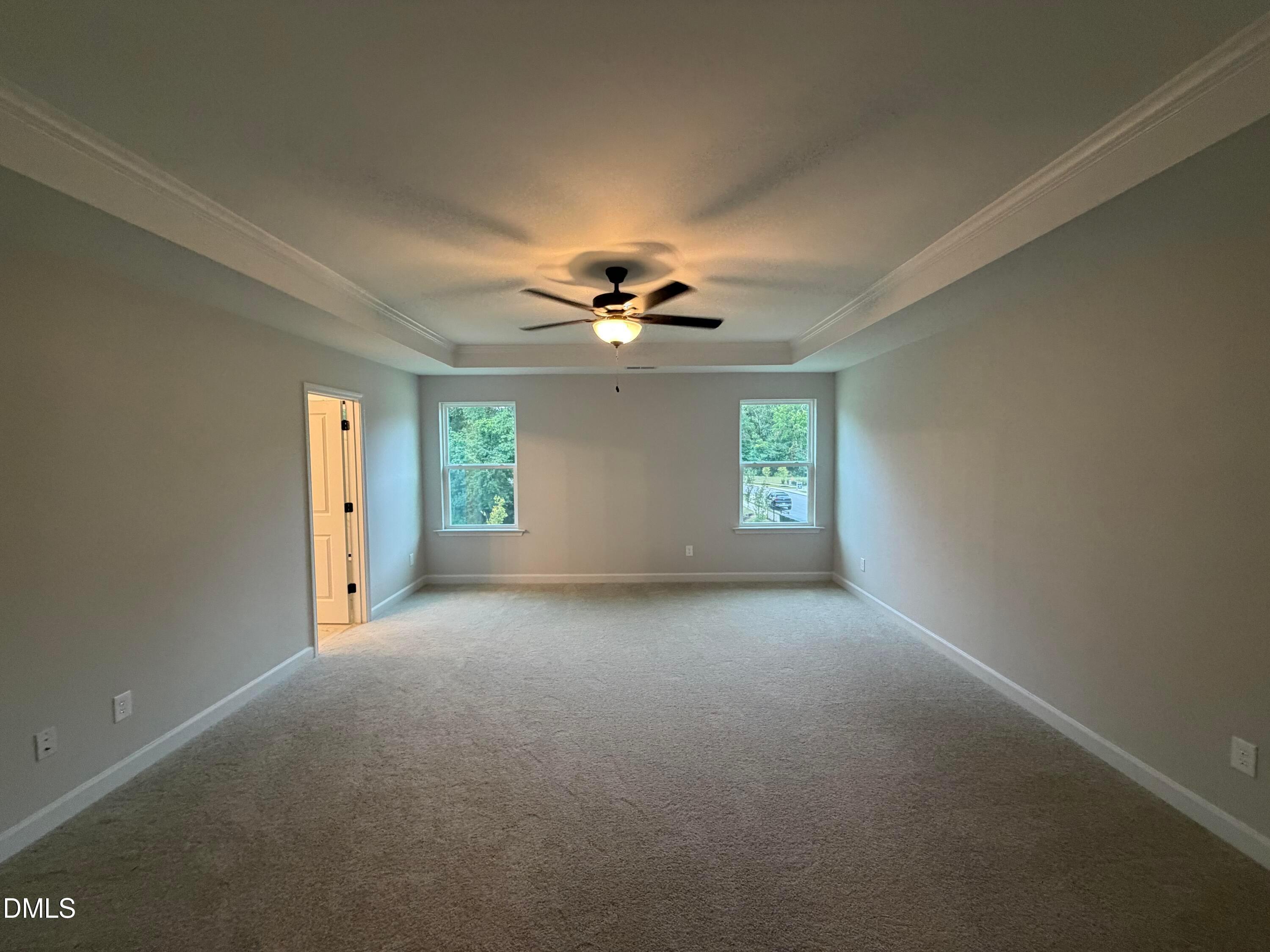 Spacious carpeted bedroom with tray ceiling, ceiling fan, and dual windows in Davidson Homes The Preston C, Wendell Ridge, NC