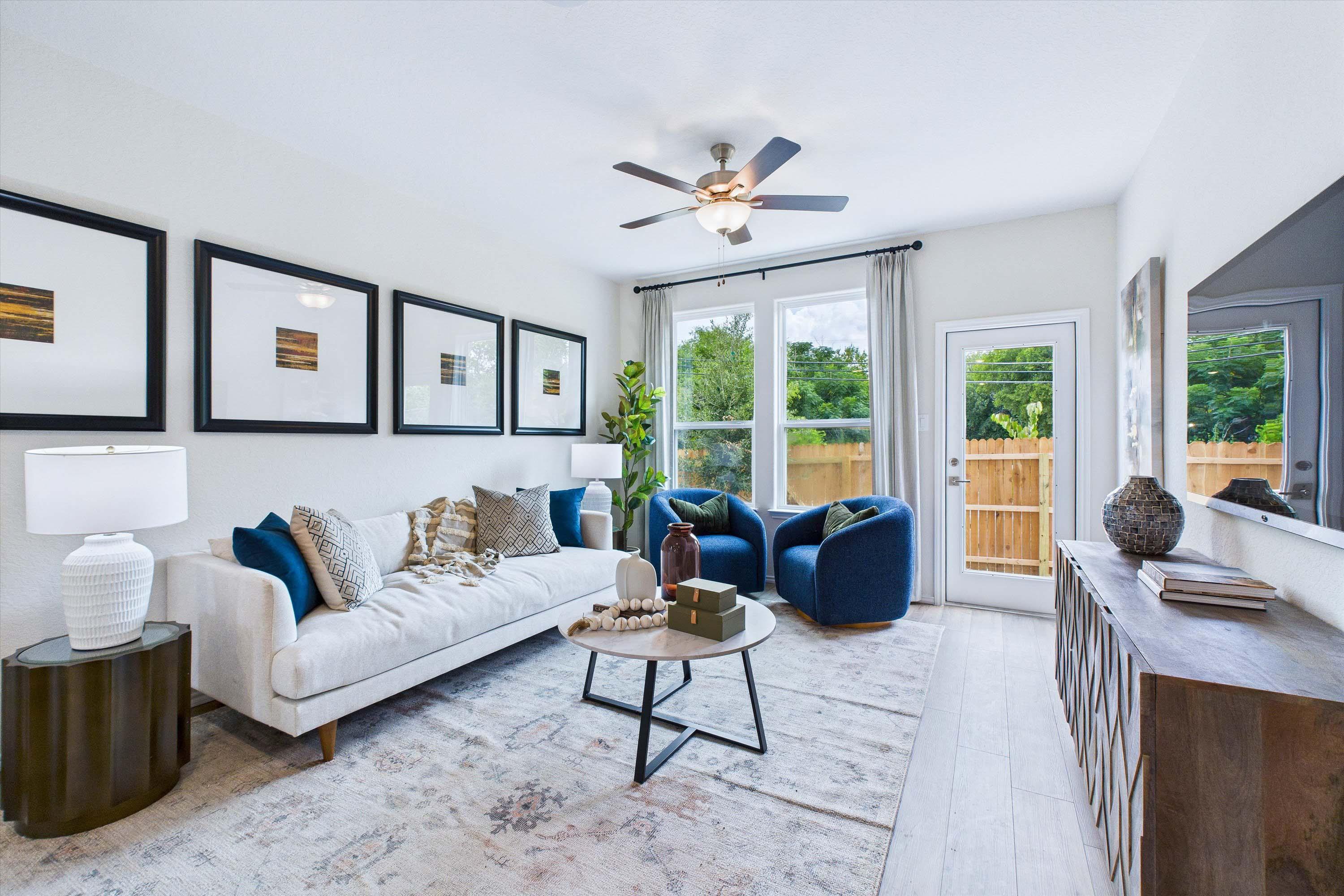 Bright, modern living room in The Gillian C featuring a neutral sofa, blue accent chairs, and an open floor plan design.