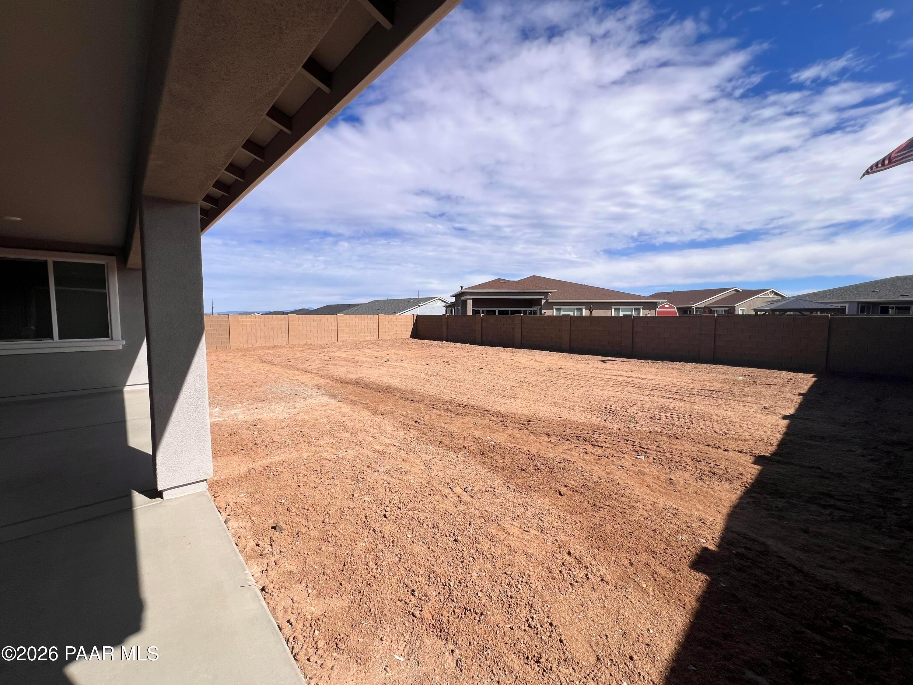 Expansive empty dirt backyard with block wall fence under covered patio in Davidson Homes The Monarch A, Westwood, Prescott, Arizona