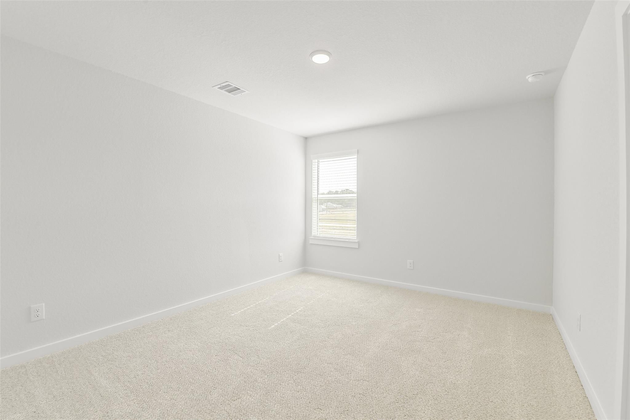 Spacious secondary bedroom with light gray walls, beige carpet, and large window in Davidson Homes San Marcos E, Cleveland Texas