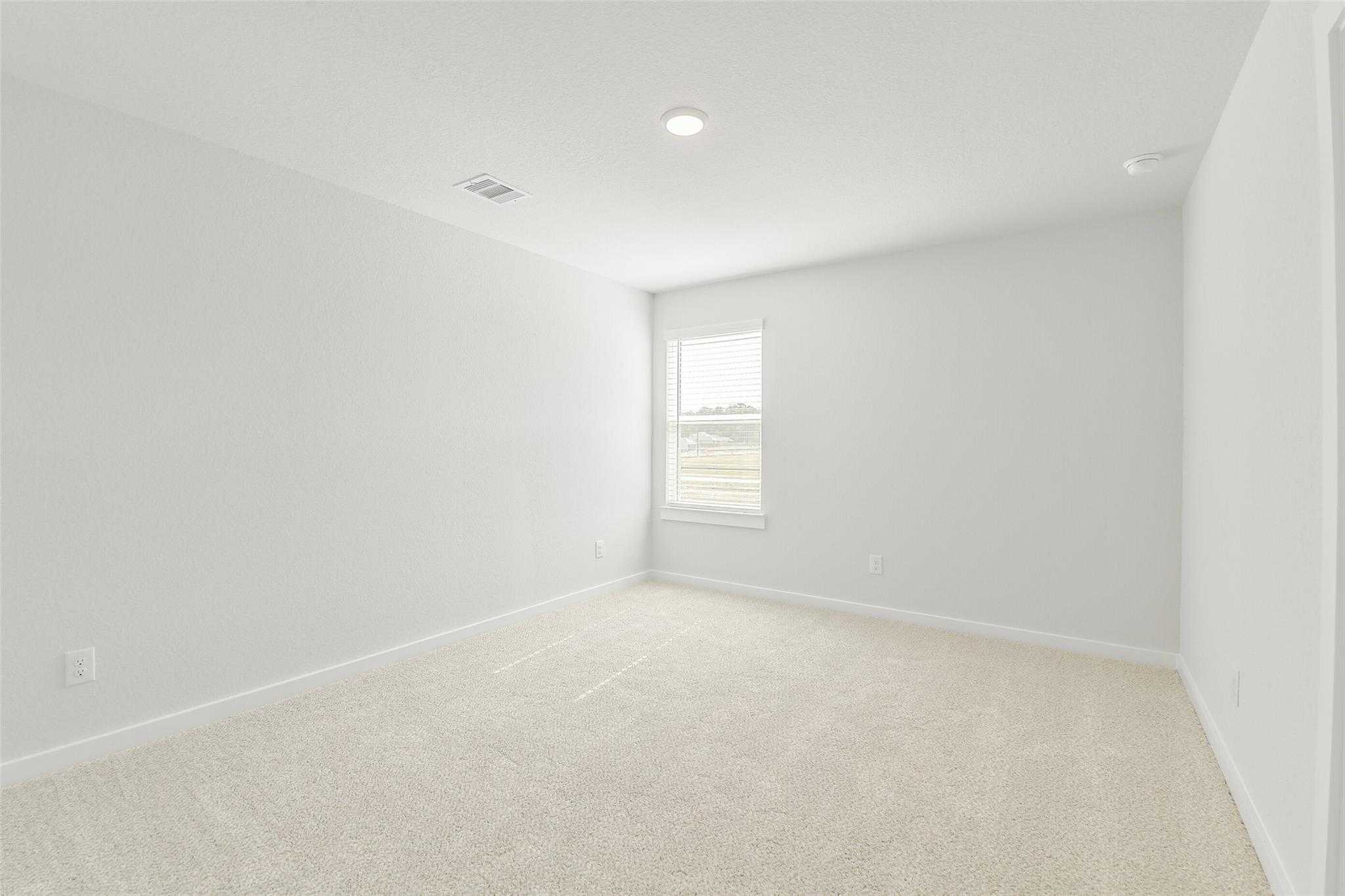 Spacious secondary bedroom with light gray walls, beige carpet, and large window in Davidson Homes San Marcos E, Cleveland Texas