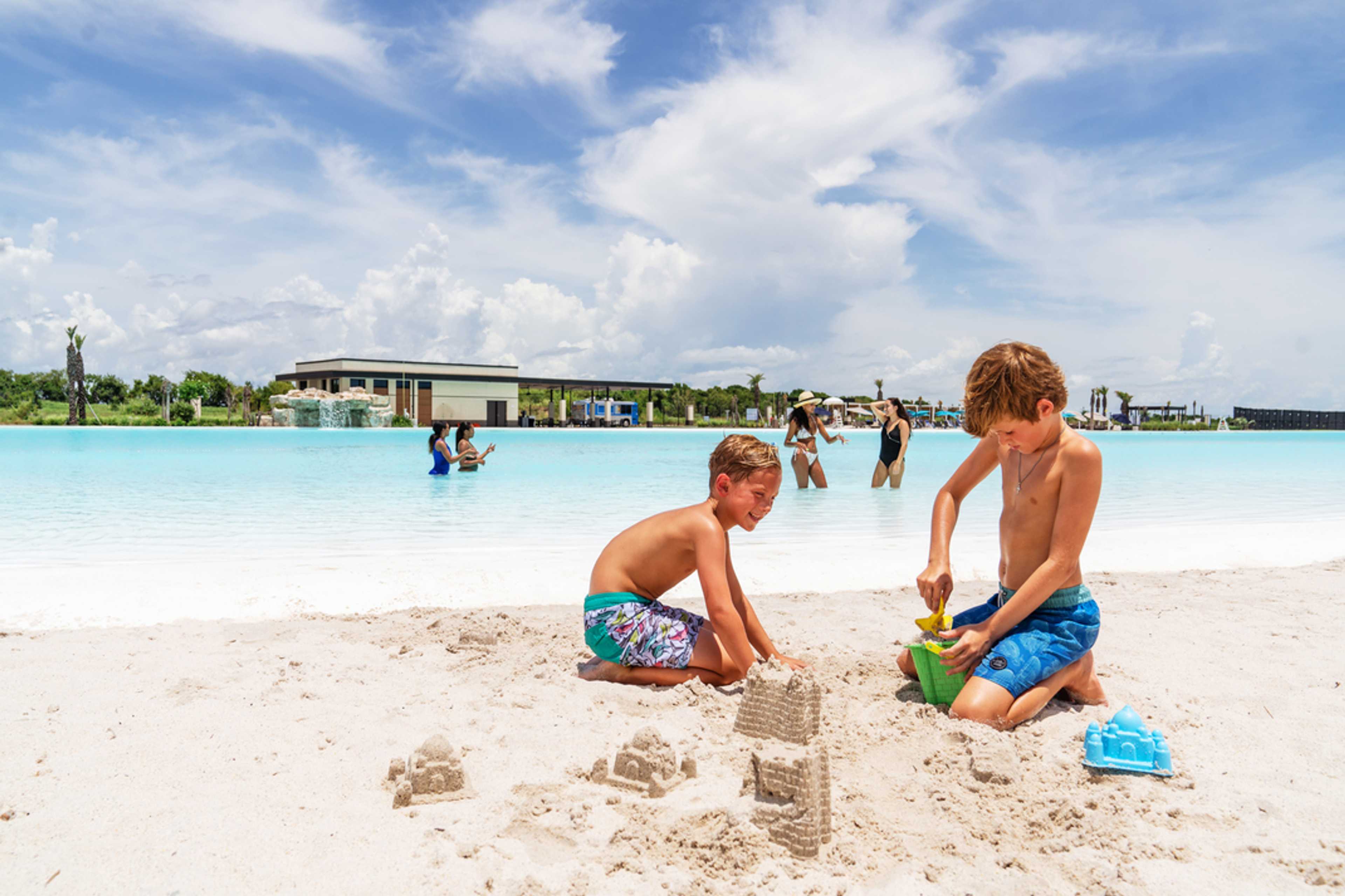 Young boys building sandcastles on white sand beach at Lago Mar lagoon in Texas City, Texas
