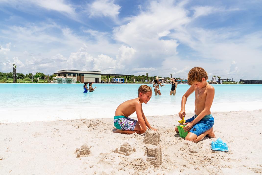Young boys building sandcastles on white sand beach at Lago Mar lagoon in Texas City, Texas