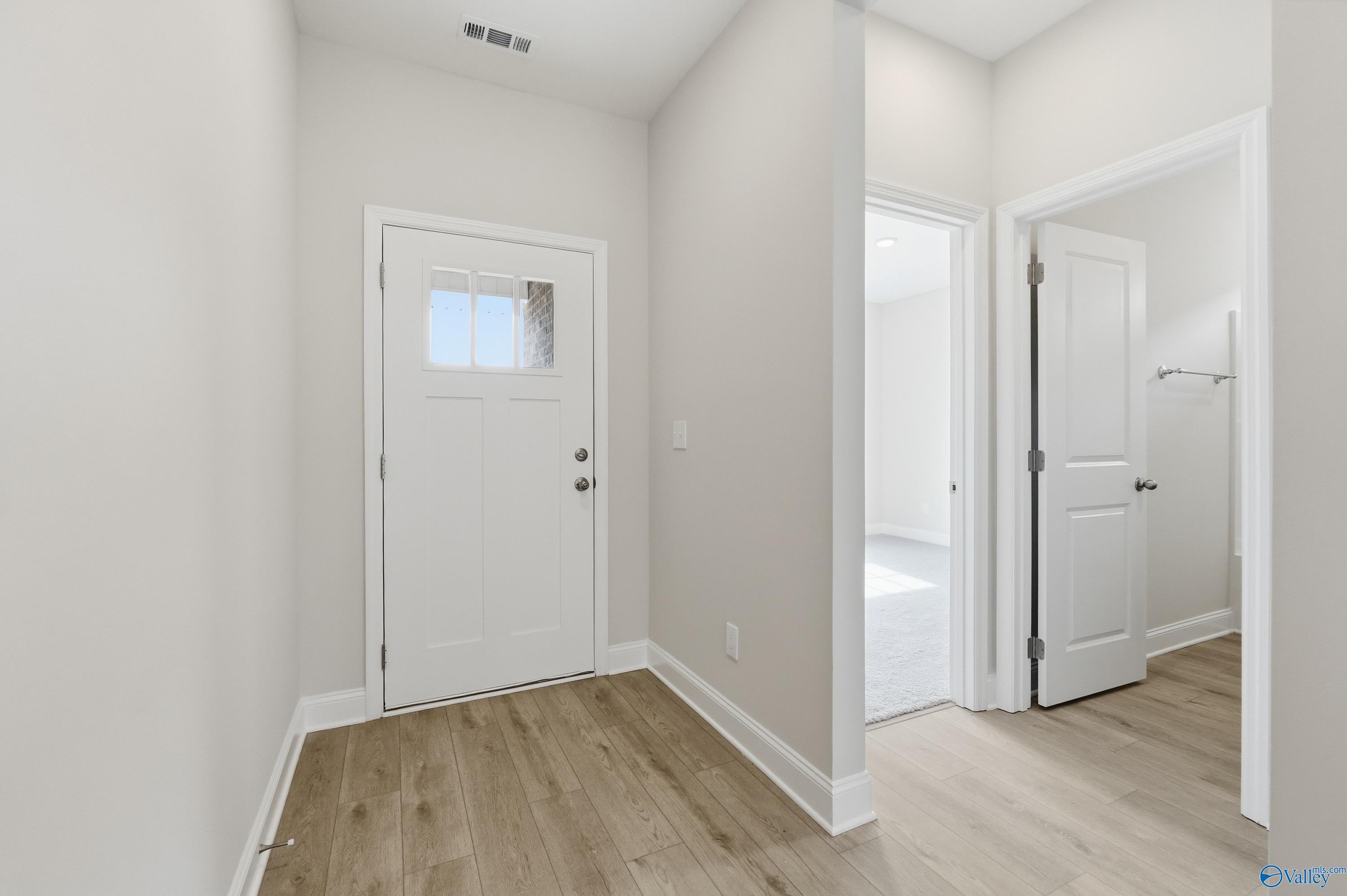 Bright entryway with white doors, light wood floors, and neutral walls in The Franklin 3-bedroom home by Davidson Homes, Meridianville AL