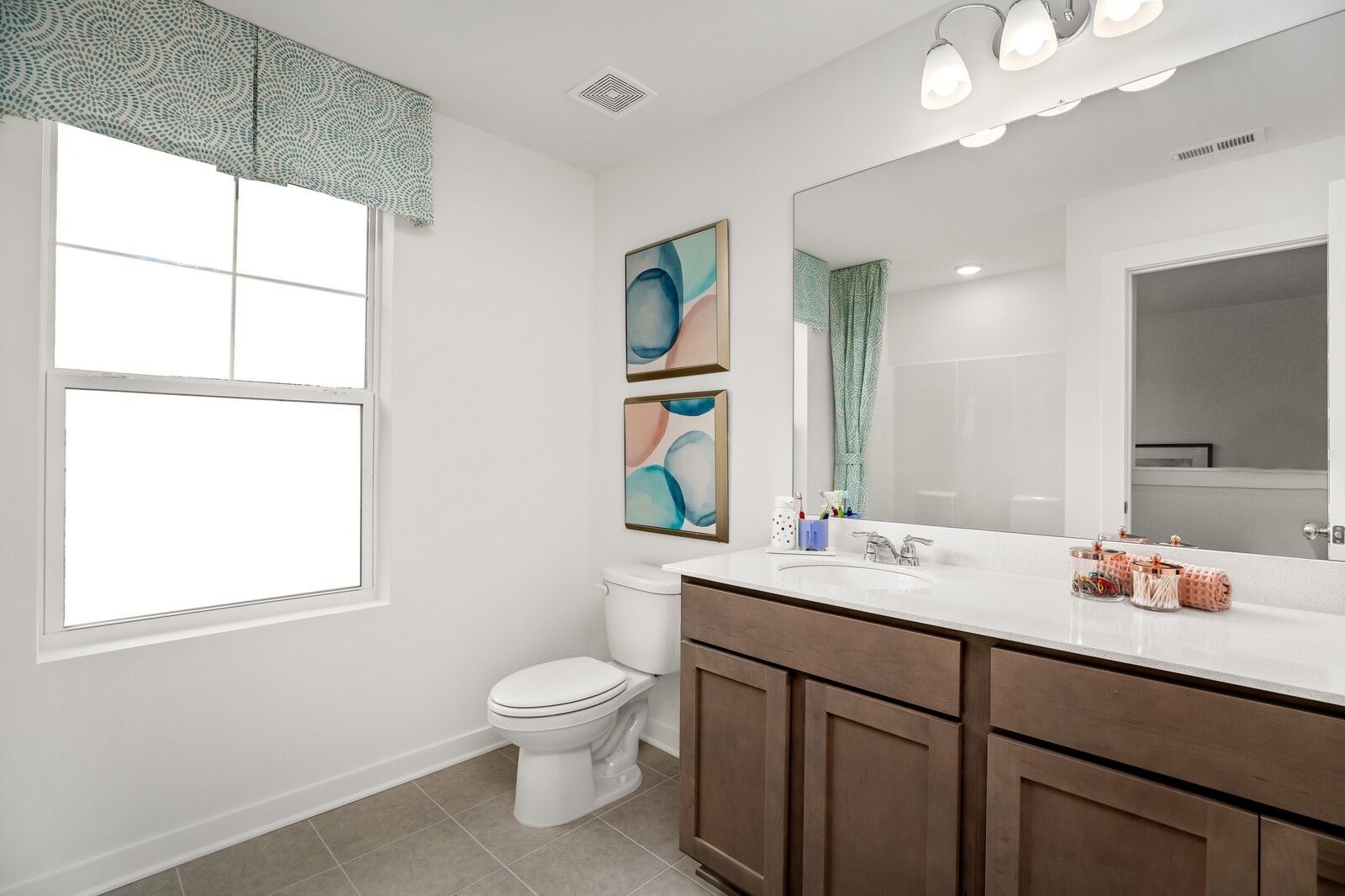 Bright guest bathroom featuring quartz vanity, large mirror, teal shower curtain, and abstract wall art in Davidson Homes The Gordon C, White House, TN