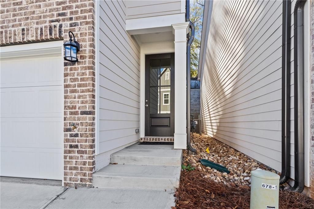Modern 2-car garage with brick accents, glass-paneled side door, and lantern lighting in Davidson Homes The Marion B, Kennesaw, GA