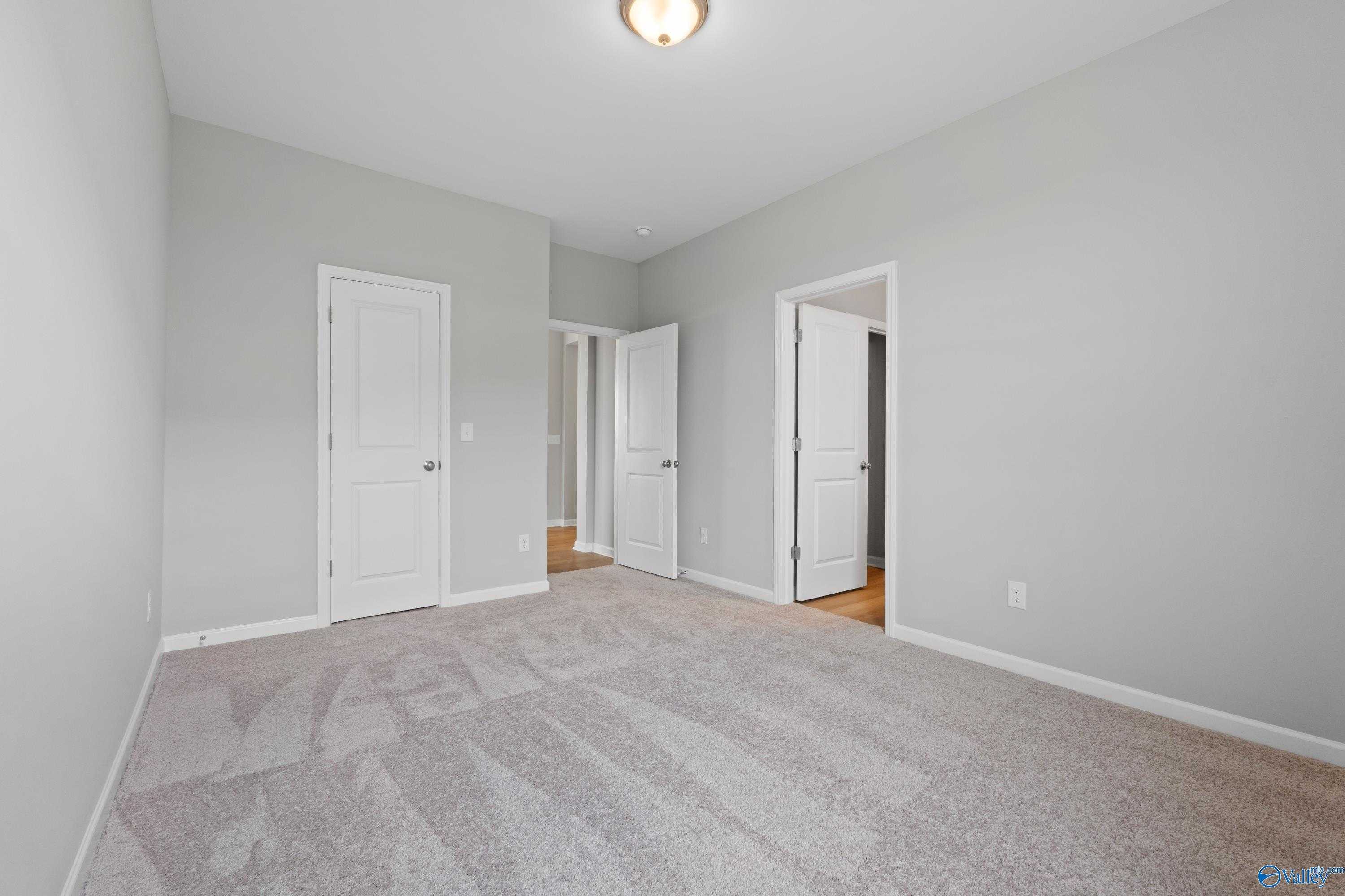 Spacious secondary bedrooms with gray walls, white doors, and plush carpet in Davidson Homes The Orion, Athens, Alabama