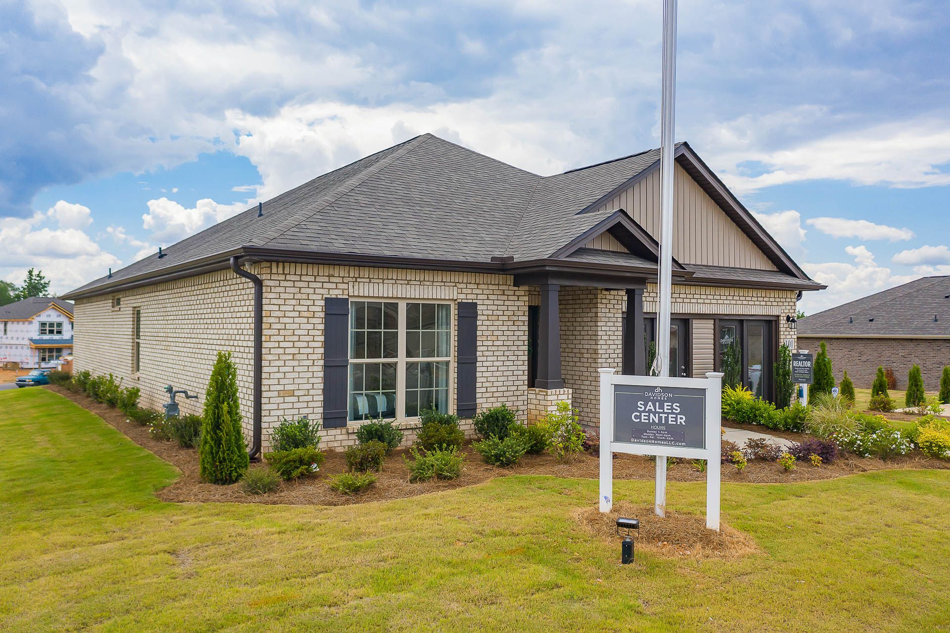 Modern brick sales center home at Heritage Heights in Madison AL with covered porch, large windows, and landscaped yard