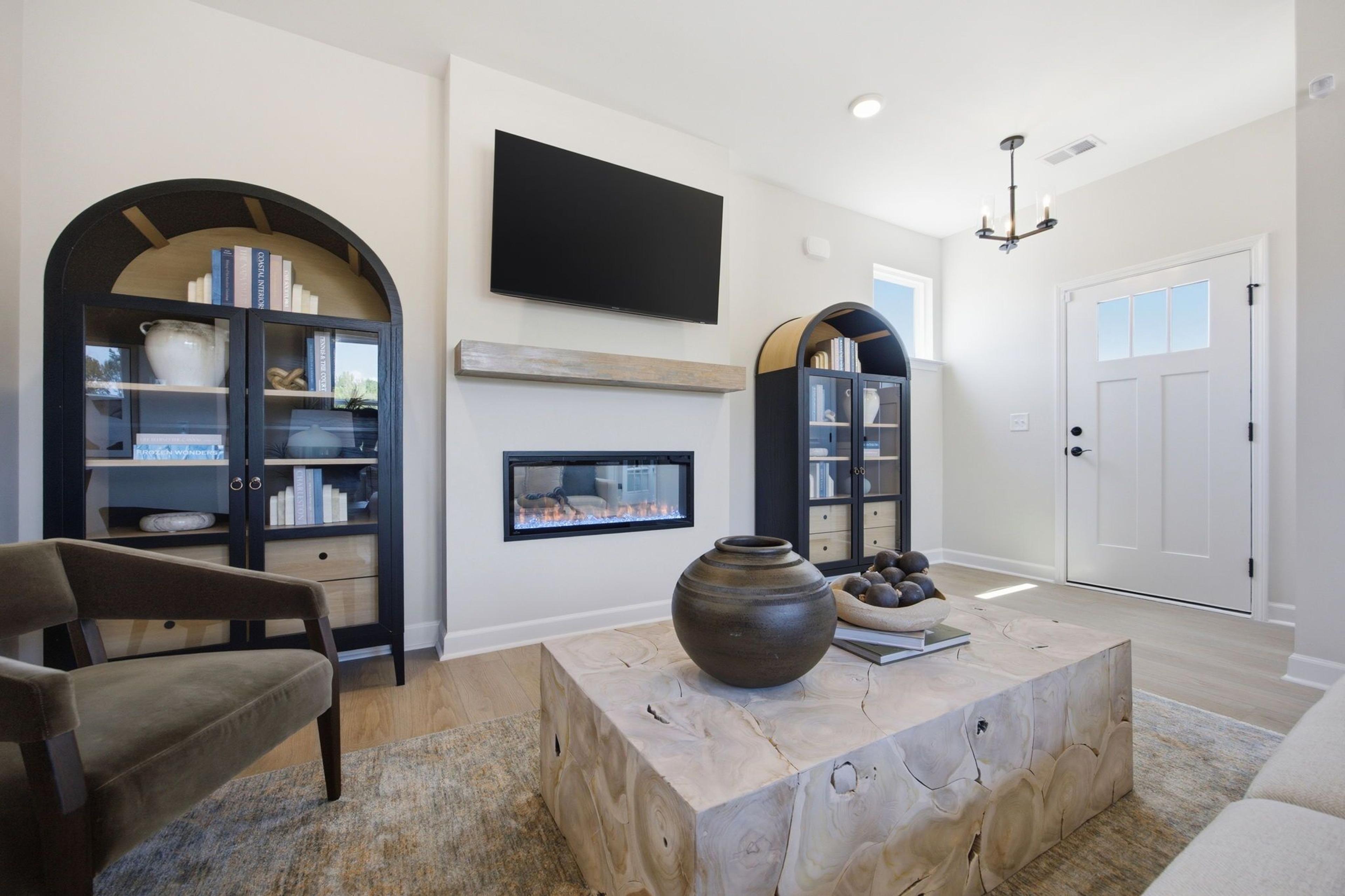Modern living room at Jackson Village in Hendersonville, TN with arched bookcases, linear fireplace, and wooden coffee table.