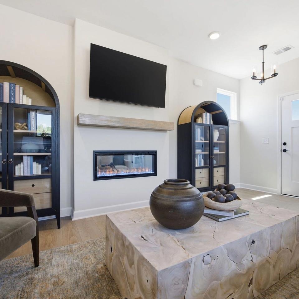 Modern living room at Jackson Village in Hendersonville, TN with arched bookcases, linear fireplace, and wooden coffee table.