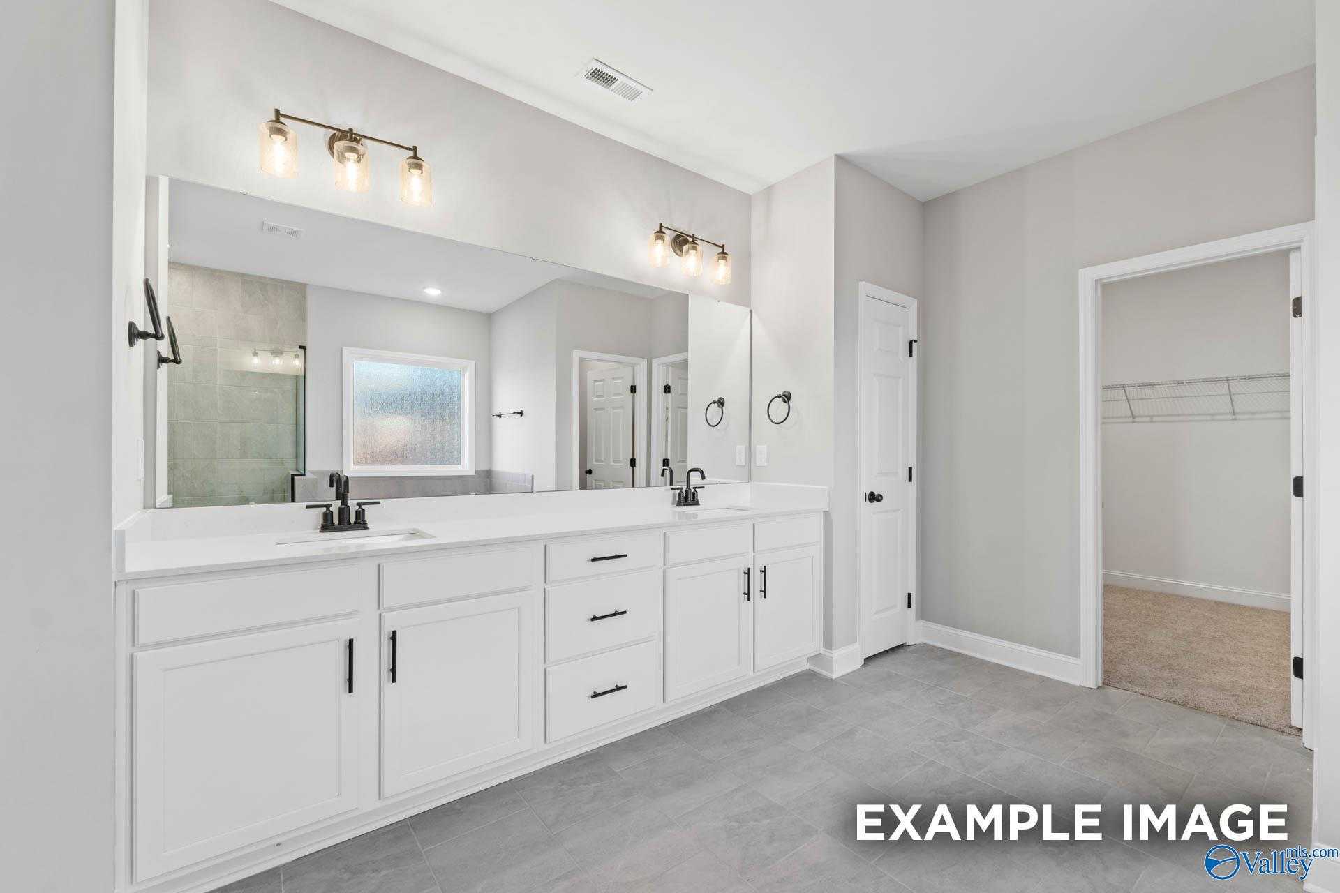 Elegant master bathroom with double white vanity, frameless glass shower, and large mirrors in Davidson Homes The Valencia, Meridianville AL