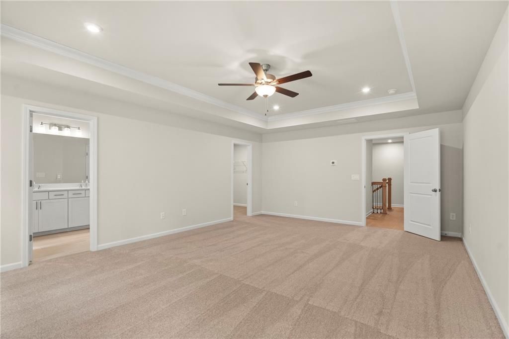 Spacious upstairs room with ceiling fan, beige walls, carpet flooring, and adjacent bathroom in The Cary A, Kennesaw, GA