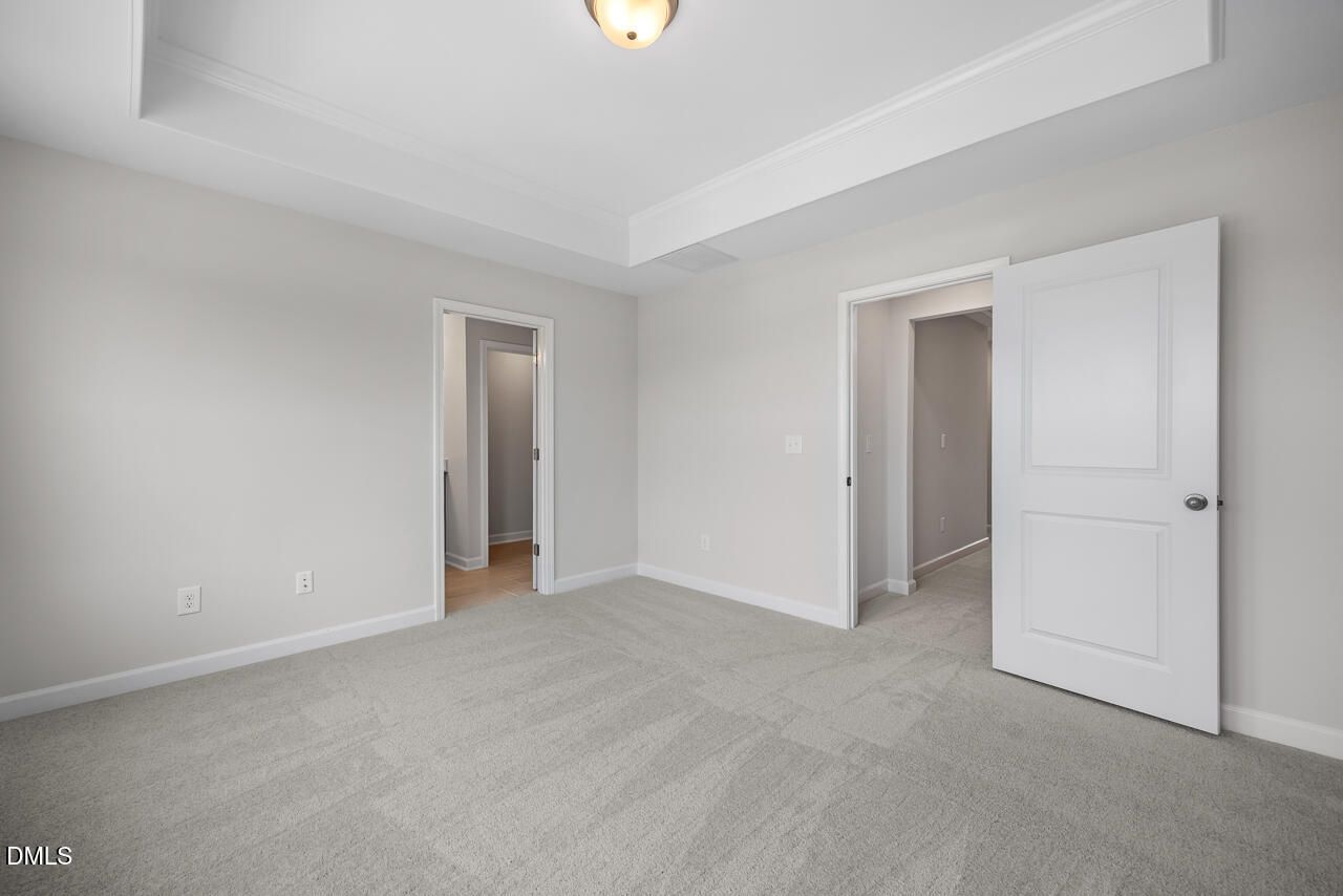 Spacious bedroom with tray ceiling and neutral carpet in The Mitchell floor plan at Forestville Yard Townhomes.