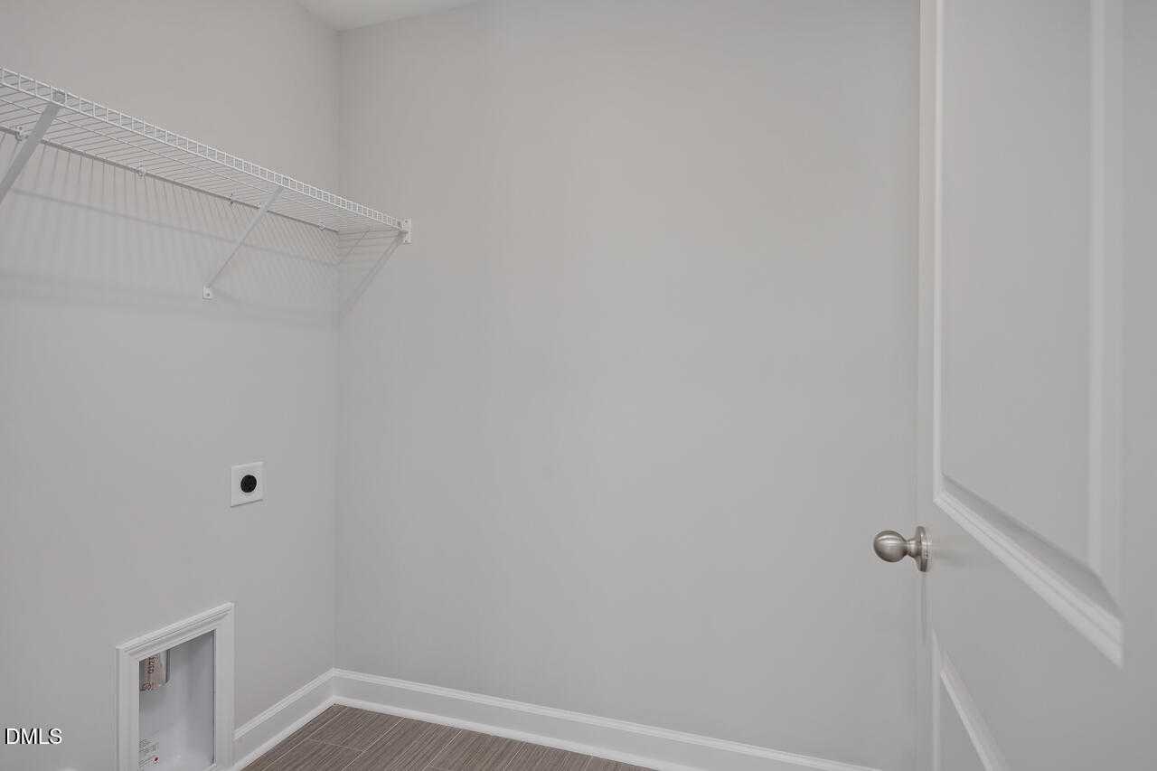 Modern laundry room with wire shelving, washer/dryer hookups, and gray walls in Davidson Homes The Graham, Fuquay-Varina, NC