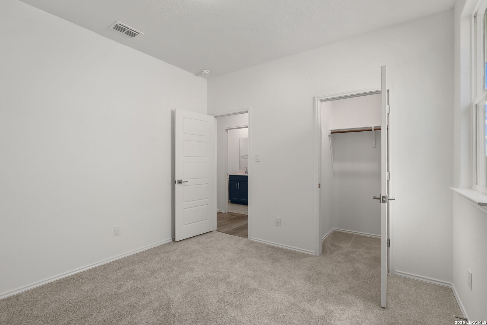 Bright secondary bedroom with en-suite bath vanity and spacious walk-in closet in Davidson Homes The Glenwood E, Elmendorf, Texas