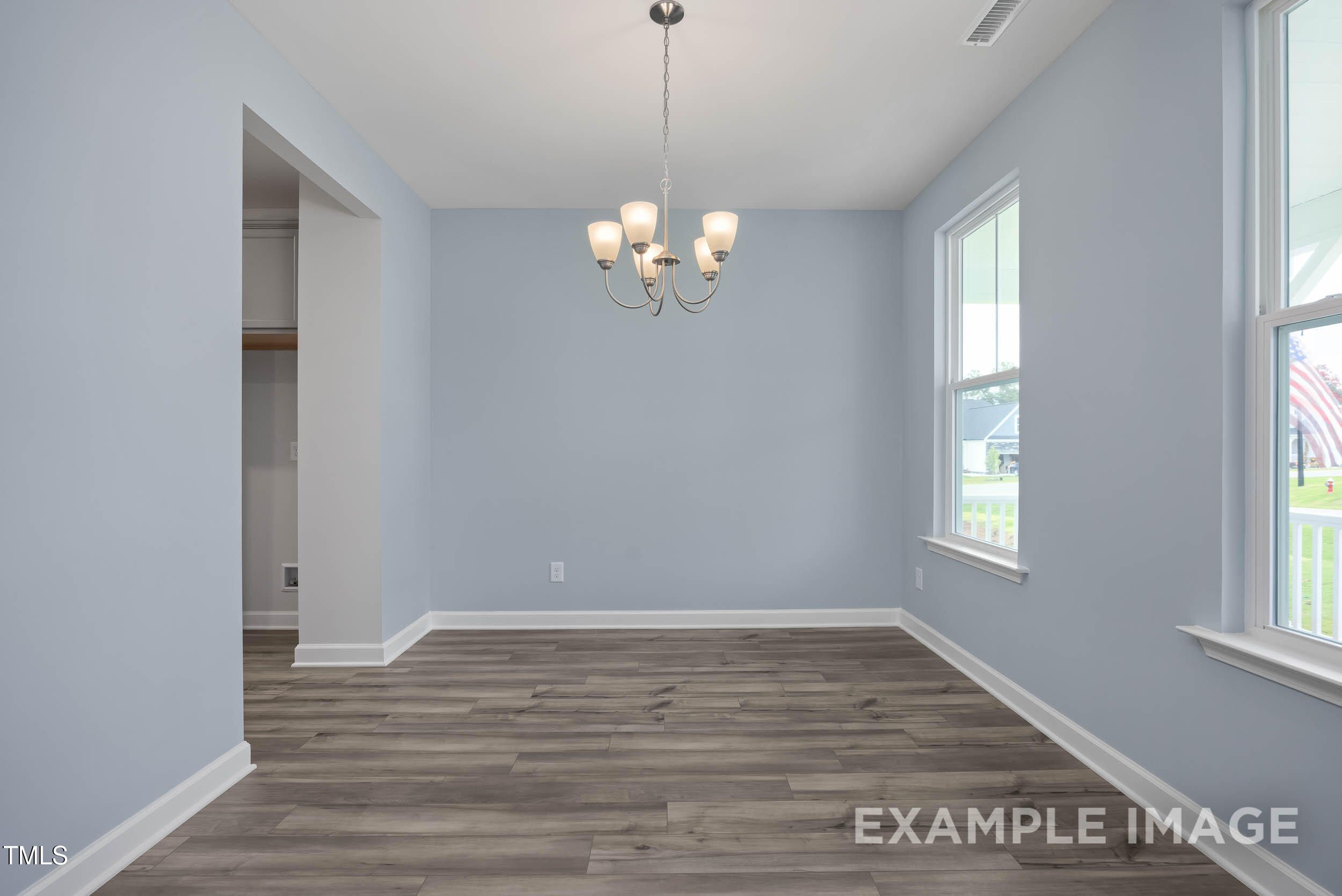 Elegant dining room with light blue walls, hardwood floors, chandelier, and large windows in The Willow E 4-bedroom home, Angier, NC