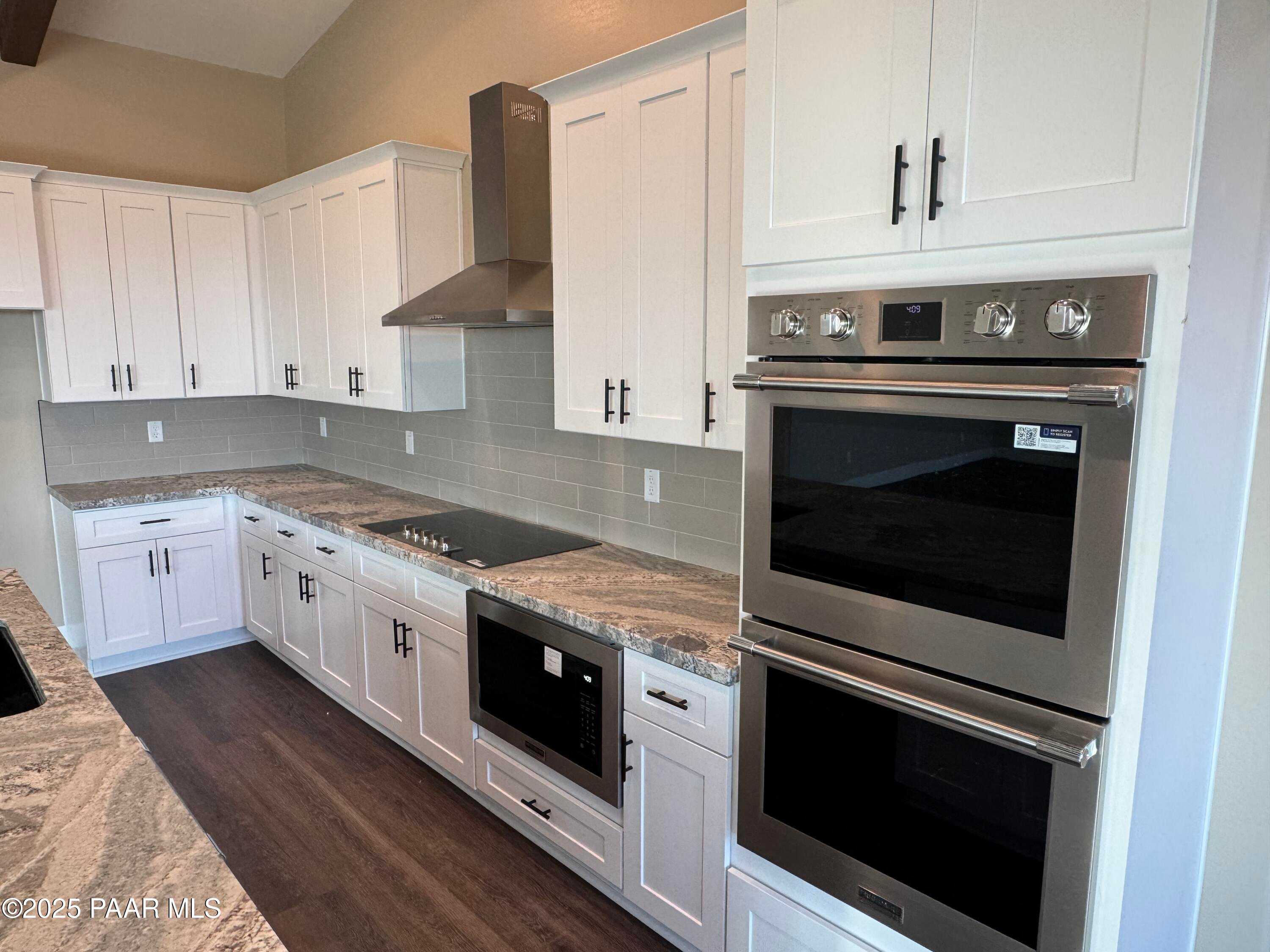 Modern kitchen featuring white shaker cabinets, granite countertops, stainless double ovens in Evermore Homes The Sunrise A, Prescott Valley, AZ
