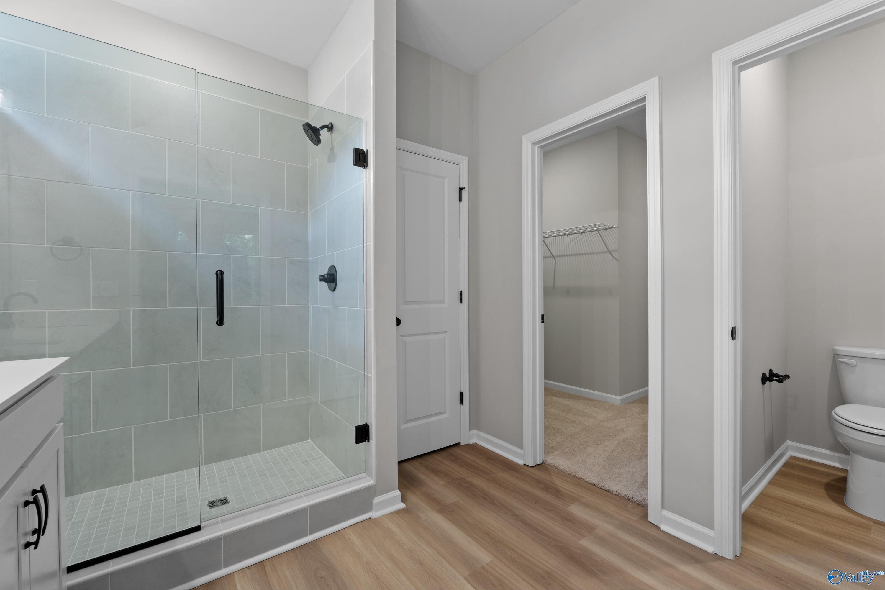 Modern master bathroom with frameless glass shower, subway tile, vanity, toilet, and adjacent walk-in closet in Davidson Homes The Phoenix, Hazel Green, Alabama